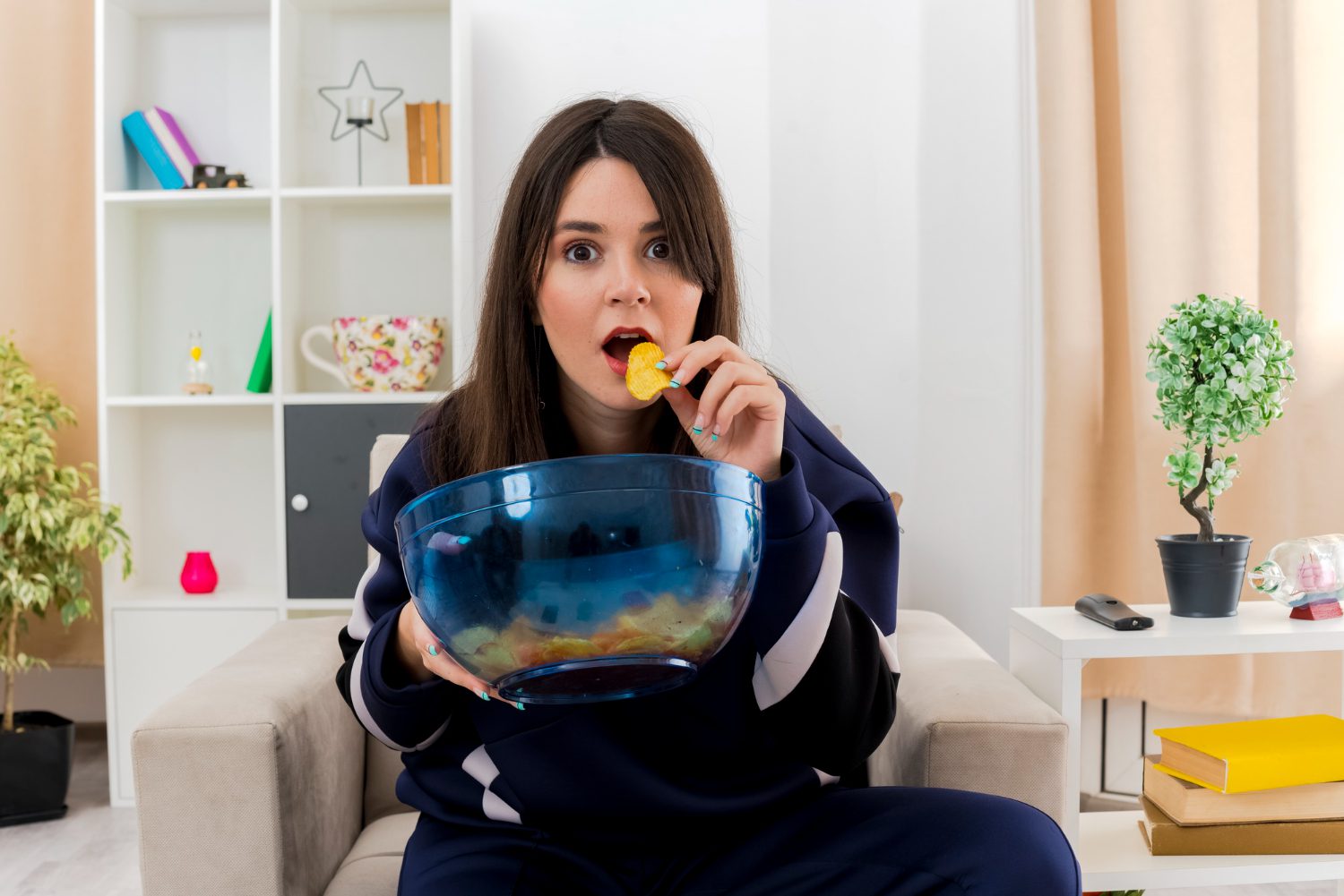 Woman eating popcorn from a large bowl while watching something.